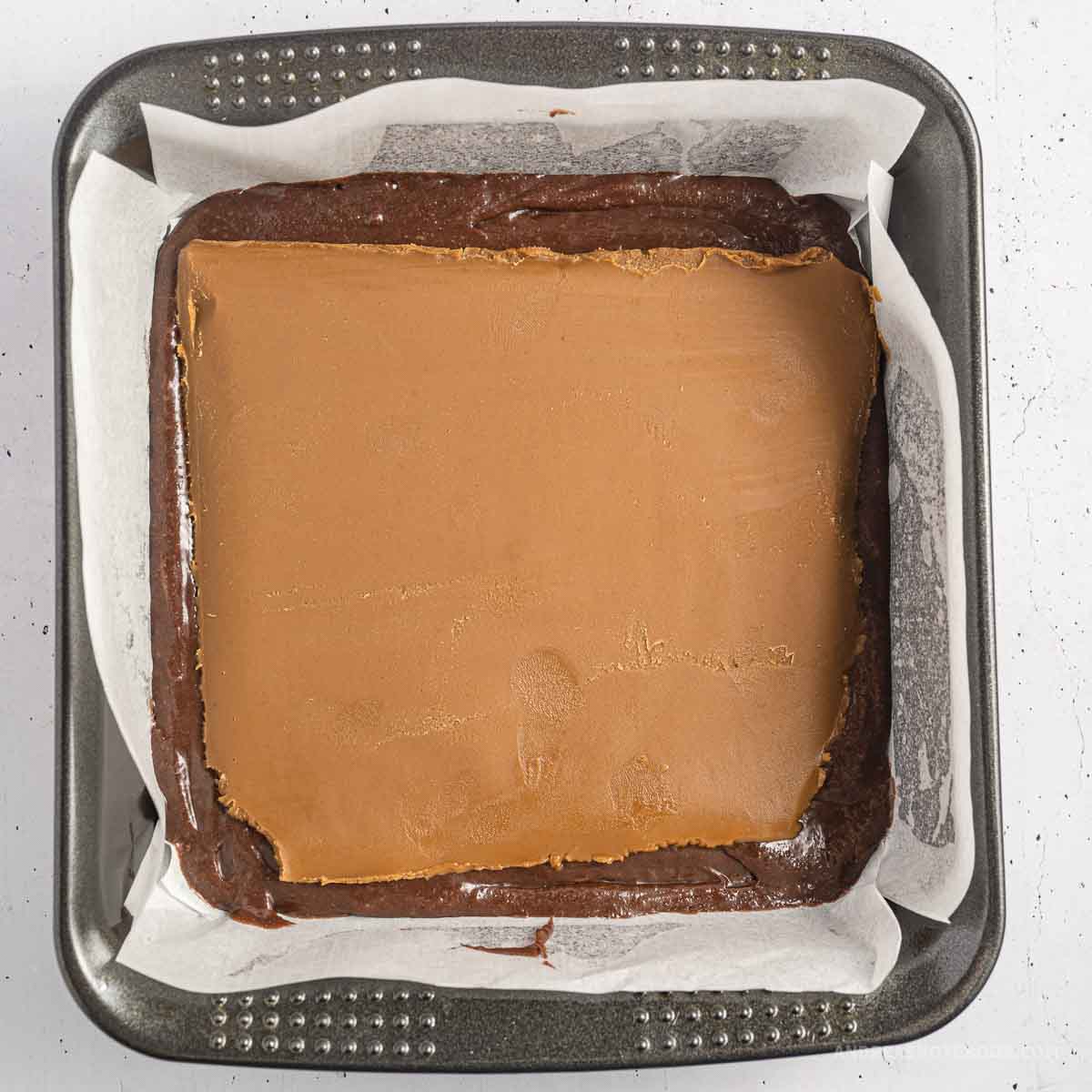 Brownie batter poured into pan with biscoff butter on top.