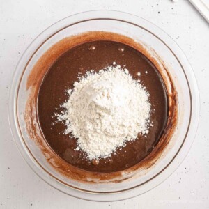Bowl full of sugar and chocolate mixture with flour on top.