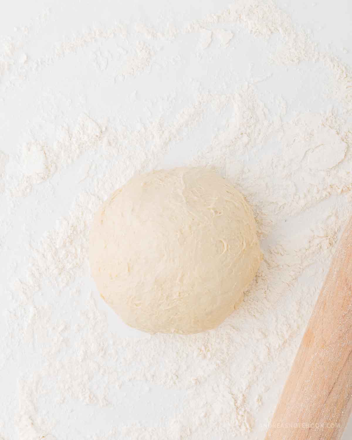Ball of pizza dough on a lightly floured surface.