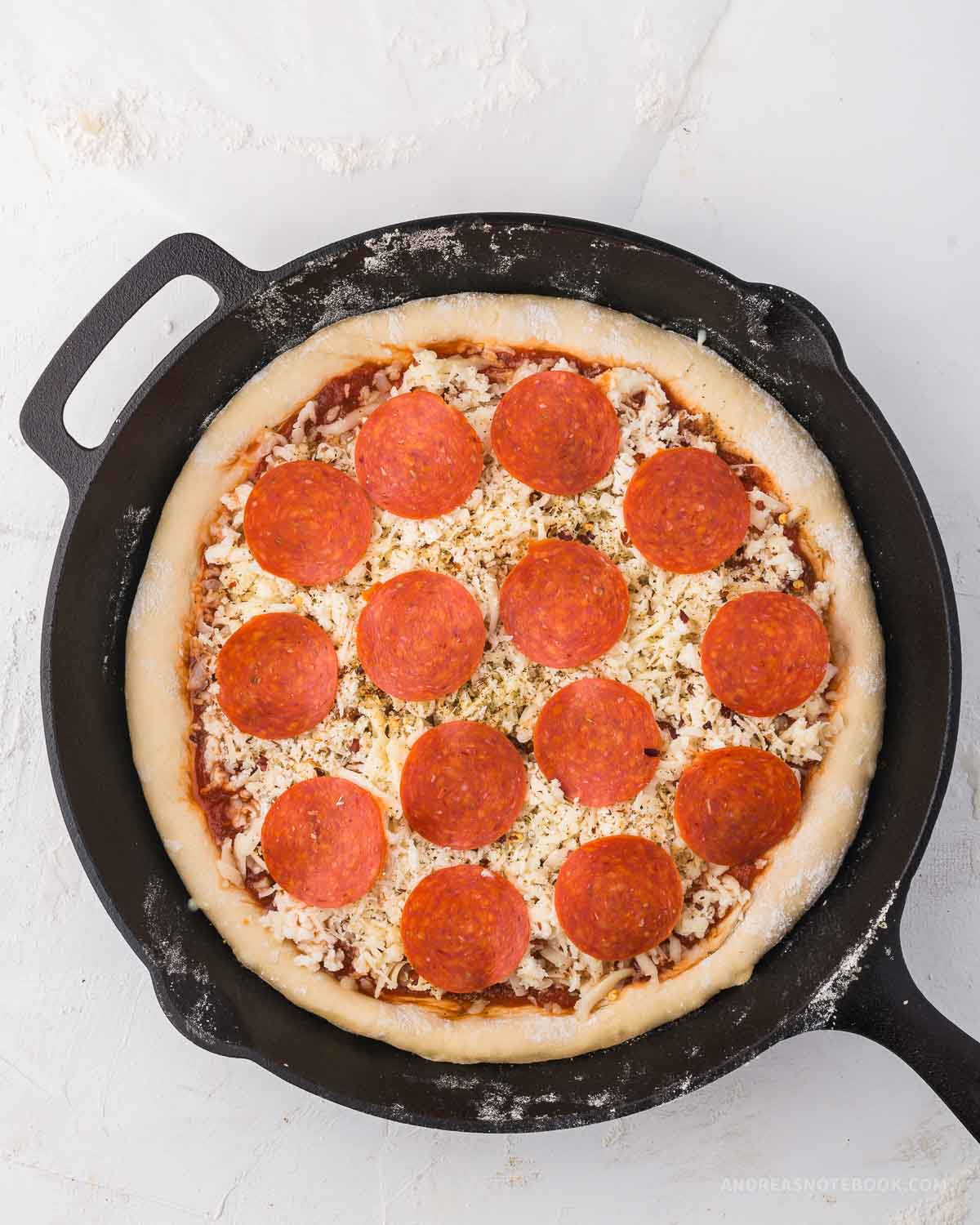 Pepperoni slices placed over cheese on pizza.