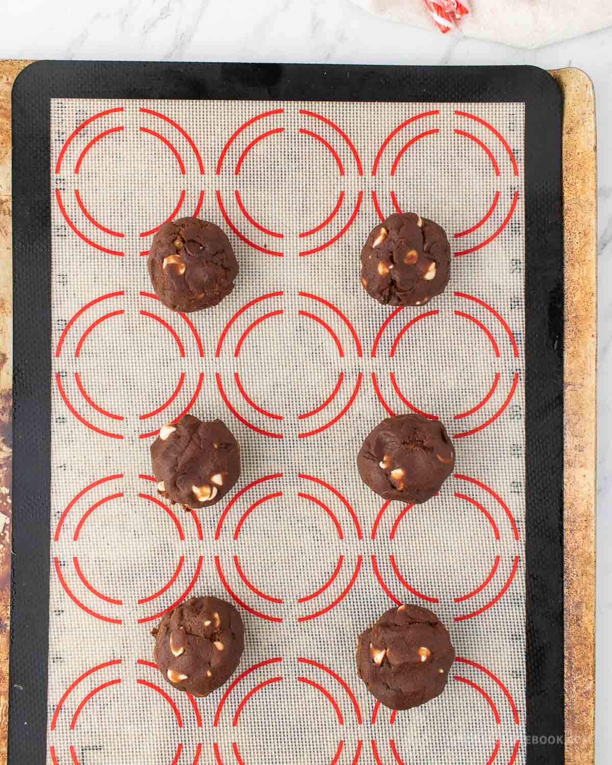 3 tablespoon size cookie dough balls rolled into a ball on a baking sheet.