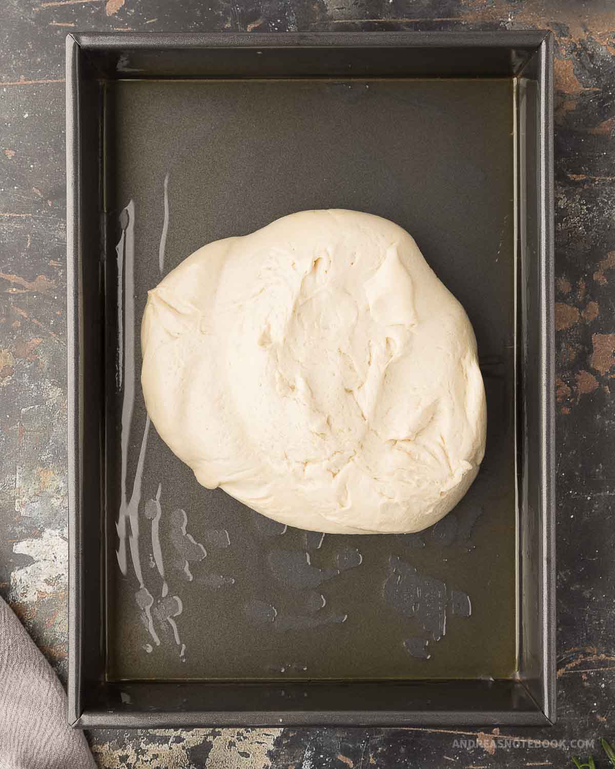 Ball of focaccia dough in an oiled 9x13-inch pan.