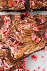 Pile of peppermint bark brownies with crushed candy canes on top.