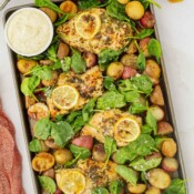 Baking sheet full of cooked honey lemon chicken and roasted potatoes and spinach.