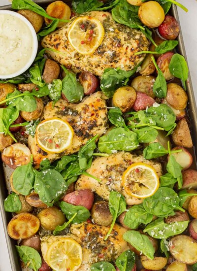Baking sheet full of cooked honey lemon chicken and roasted potatoes and spinach.