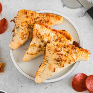 Three air fryer pepperoni calzones (hot pockets) on a plate.