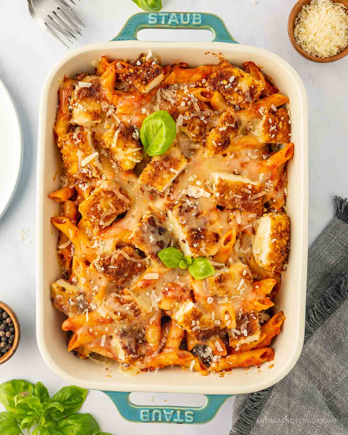 Baked chicken parmesan pasta casserole garnished with basil leaves.