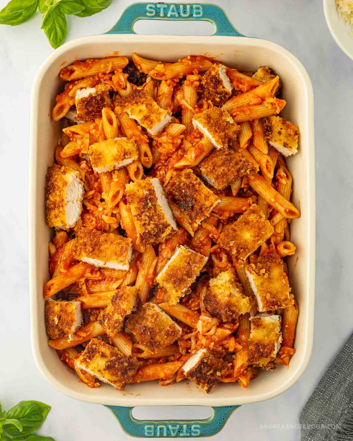 Casserole dish with chicken bites on top of penne pasta.