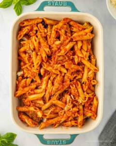 Casserole dish with saucy penne noodles on top.