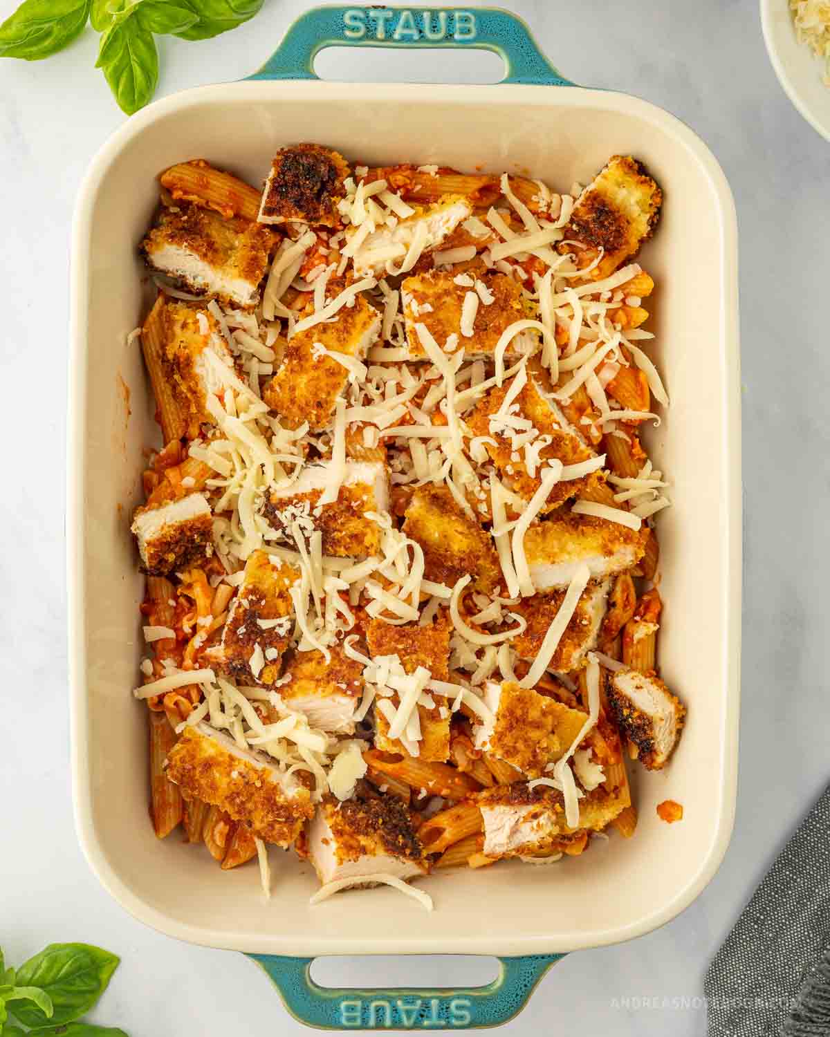 pasta, parmesan chicken and mozzarella cheese in a baking dish.