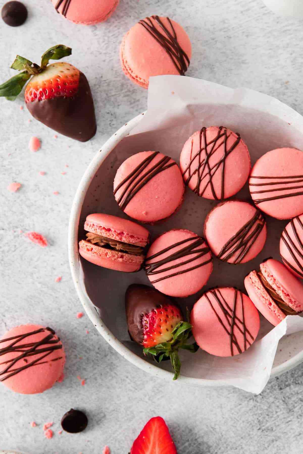 Bowl full of pink macarons with chocolate drizzle.