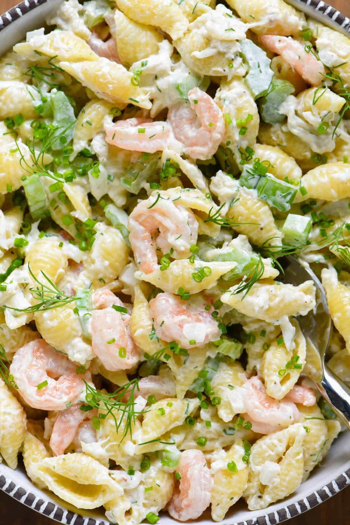 Close-up of pasta salad with shrimp, crab, lettuce and a creamy sauce.