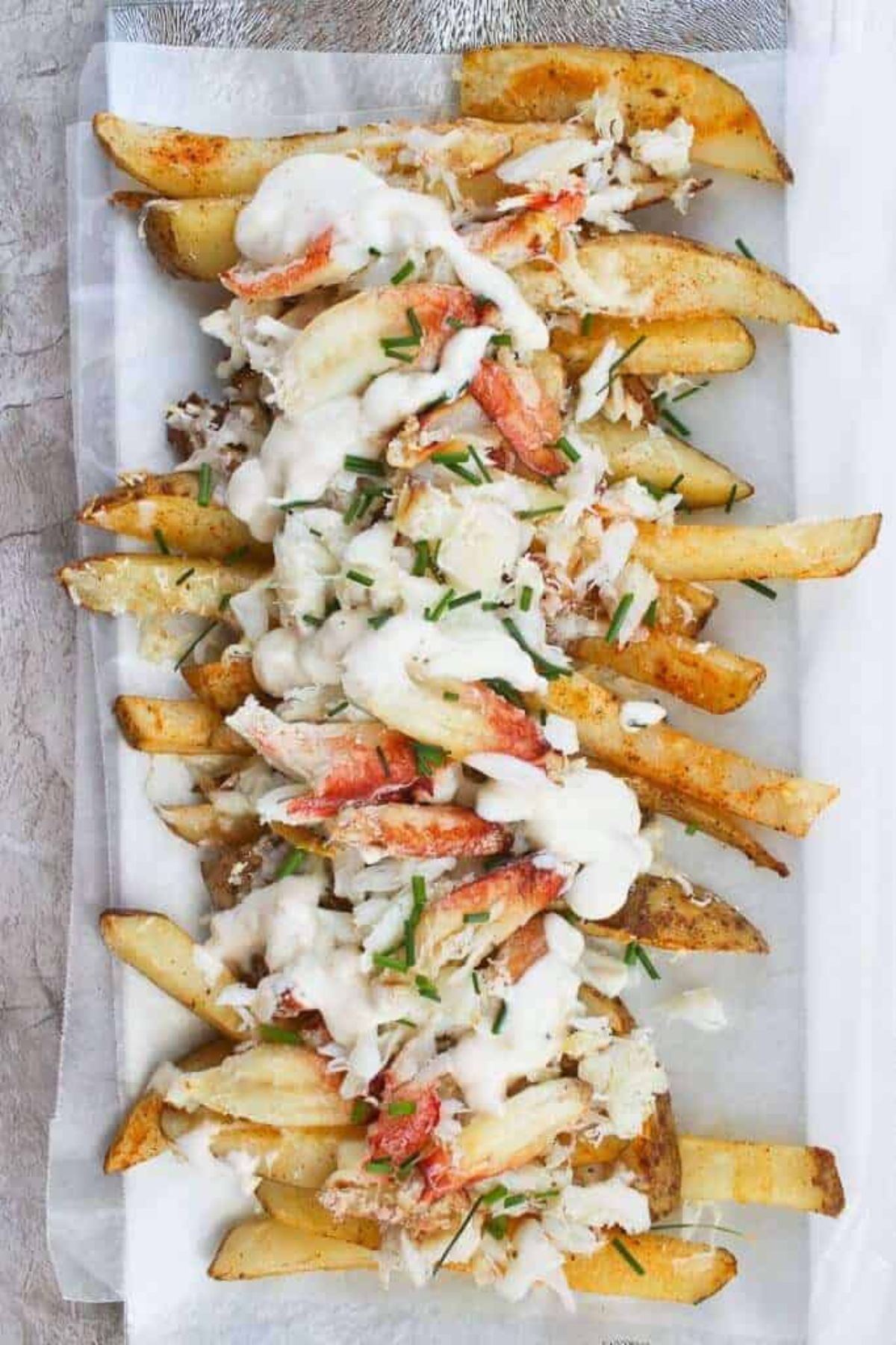 Platter of potato french fries covered in crab and sauce.