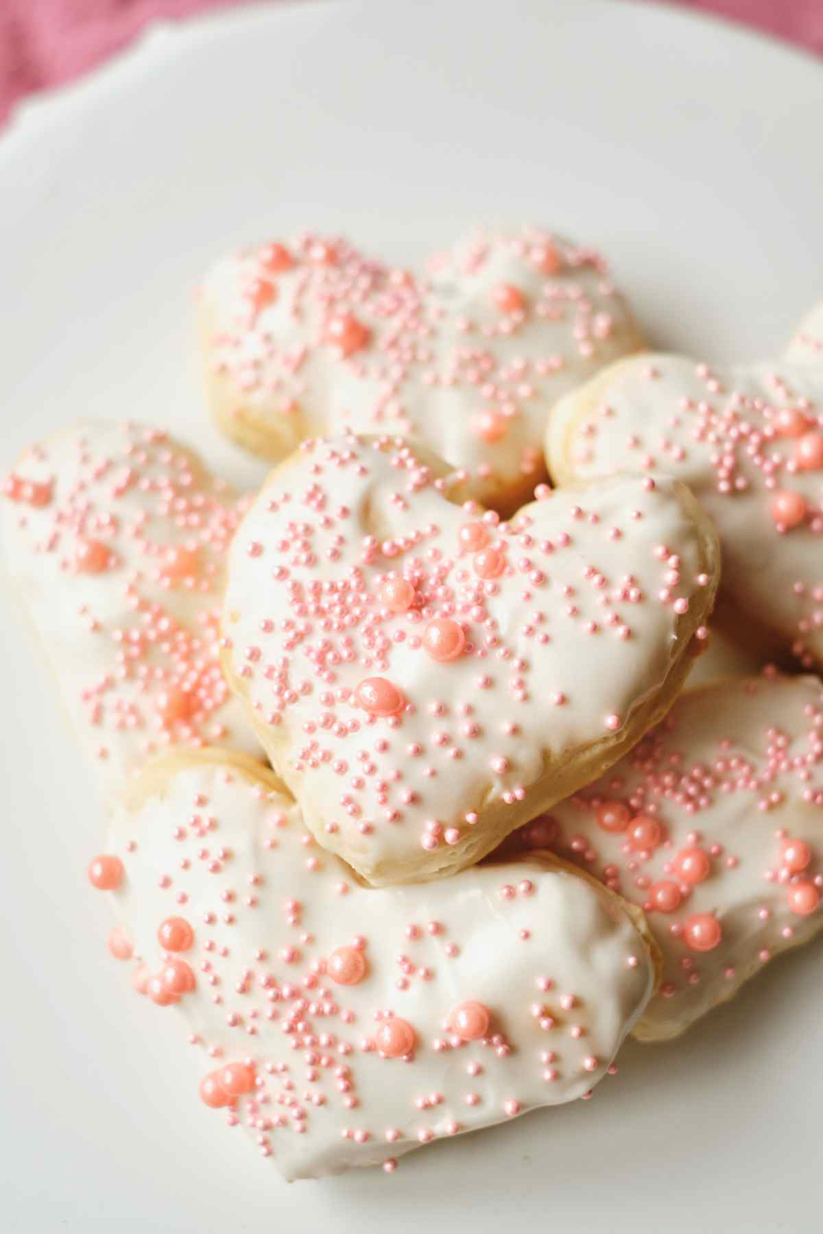 White icing covered donuts cooked in an air fryer and topped with pink sprinkles.