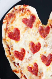 Close-up of a heart shaped pizza with heart shaped pepperoni for valentine's day.