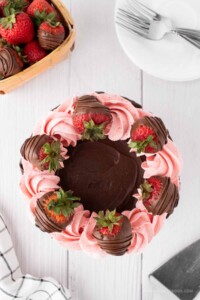 Chocolate covered strawberries on top of cake.