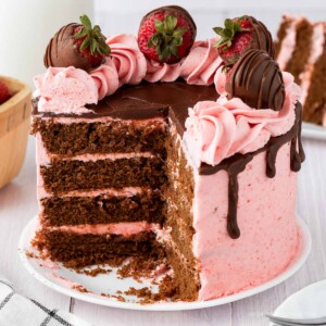 4 layer chocolate cake with strawberry frosting topped with chocolate ganache and chocolate covered strawberries.