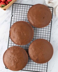 4 round cakes cooling on a cooling rack.