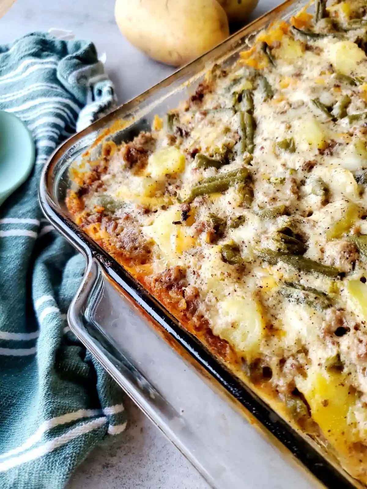 Ground beef, potato and green bean casserole without creamed soups in a casserole dish.