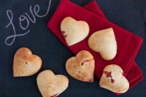 6 hear shaped empanadas with a little bit of strawberry juice dripping out.