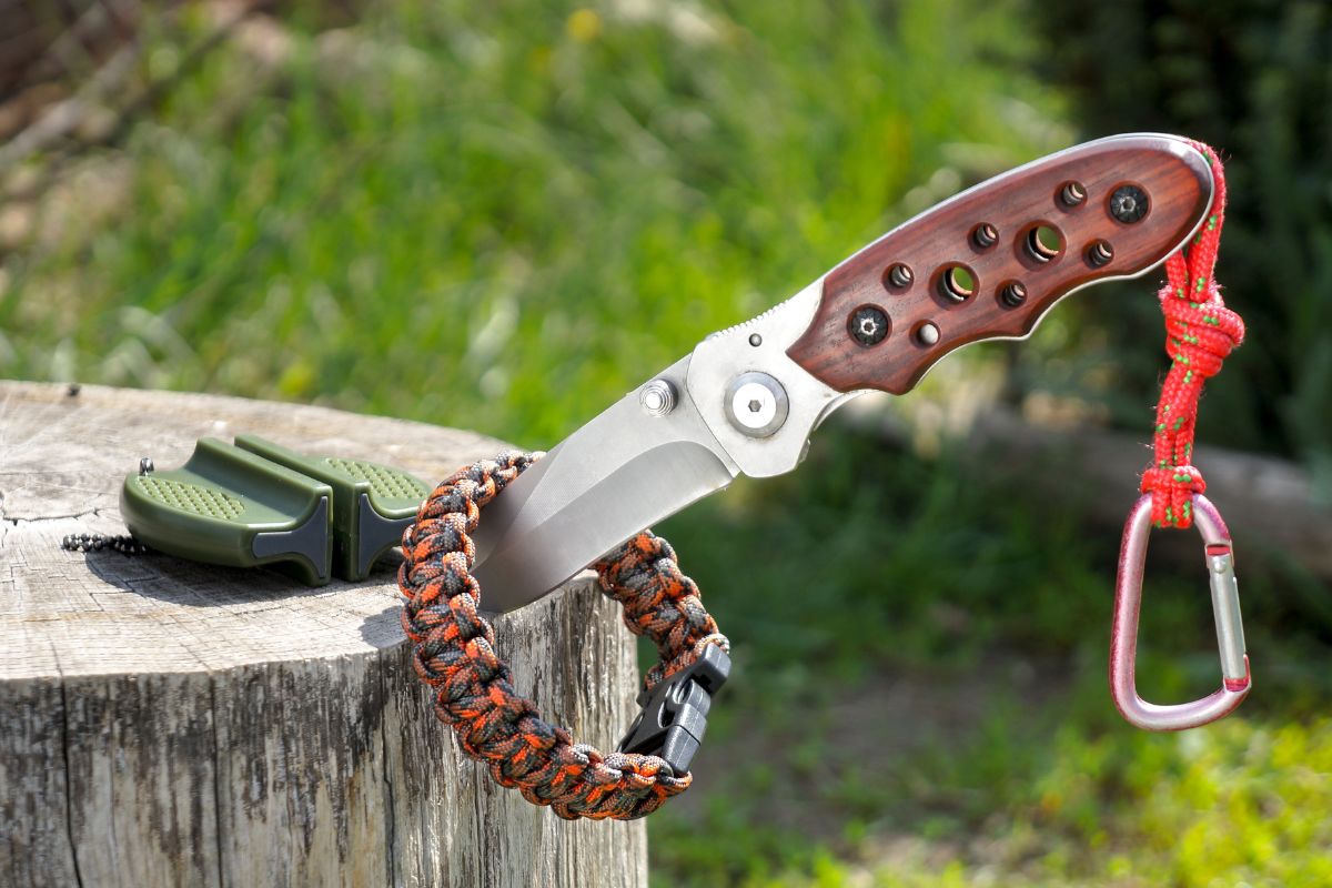 Knife stabbed into a tree stump inside a paracord bracelet are part of a zombie apocalypse survival kit.