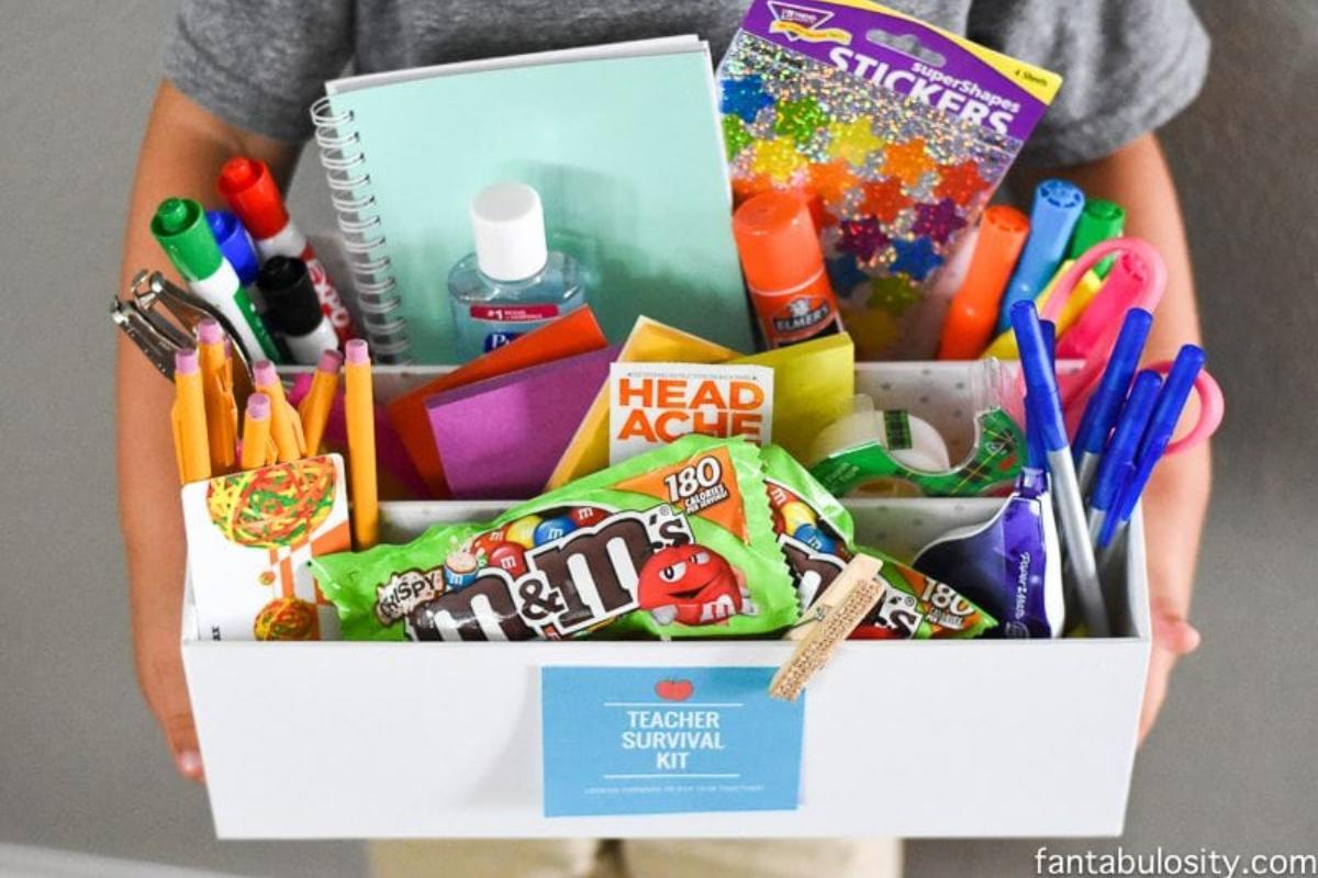 Box full of gifts for teacher with printable tag on front for teacher survival kit.