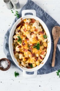 Oval casserole dish full of bacon, chicken, pasta and ranch seasoning topped with cheese.