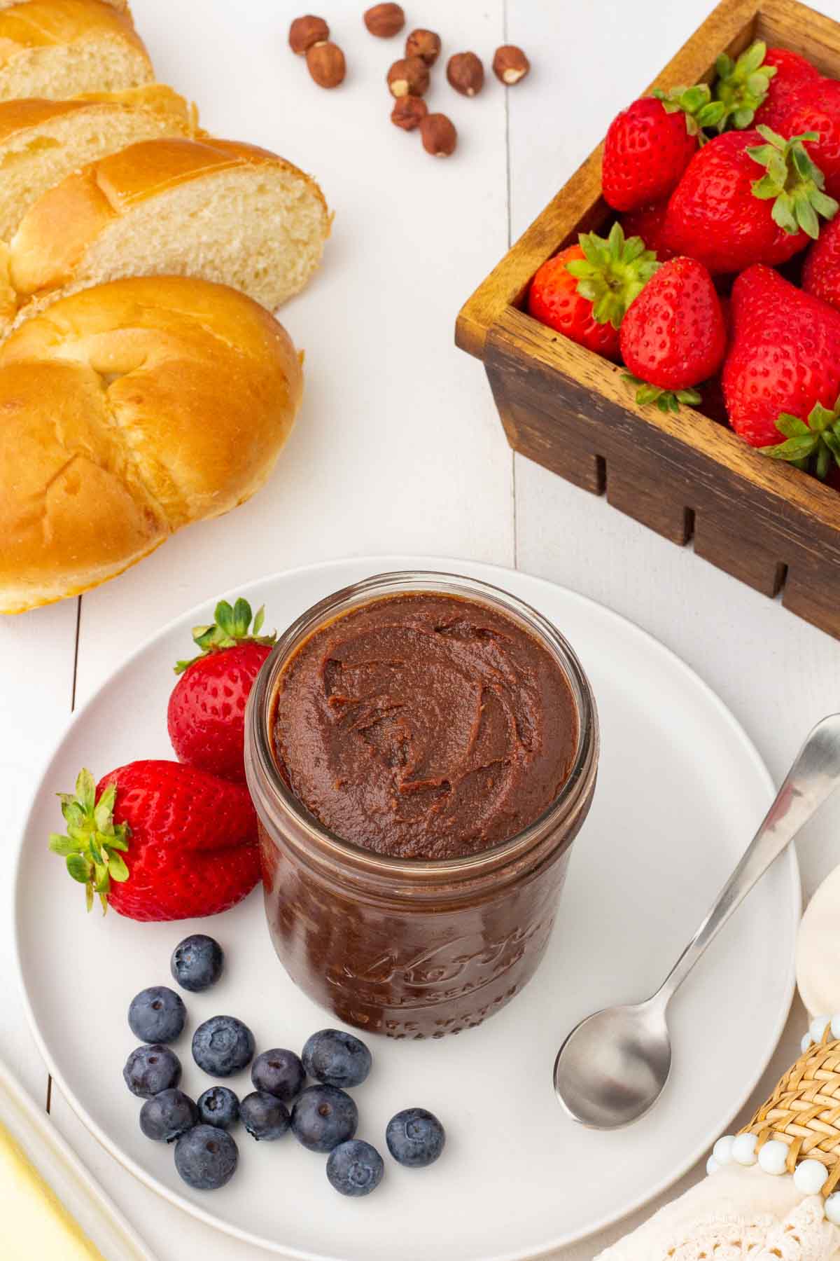 Jar of healthy homemade nutella on a plate with fresh berries.