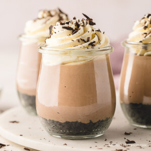 3 jars full of layered no bake nutella cheesecake topped with whipped cream and chocolate.